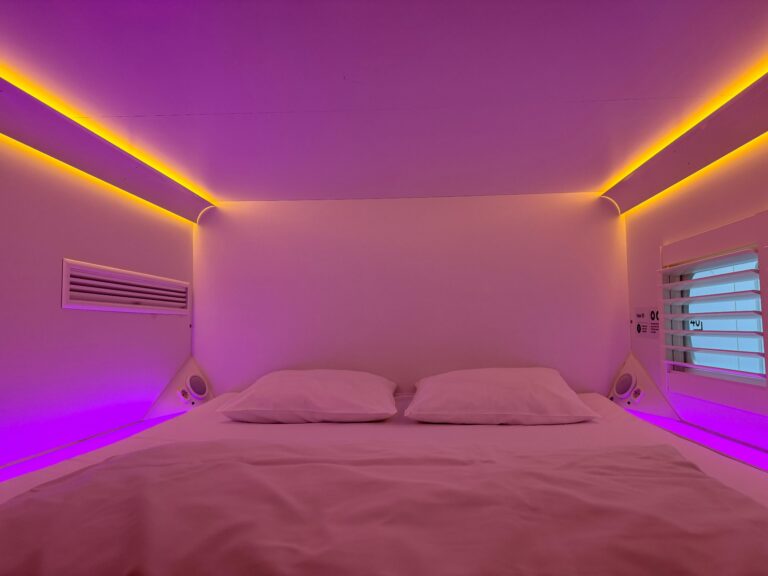 Cozy capsule hotel room with vibrant ambient lighting and minimalistic design.