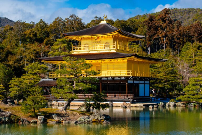 Scenic view of the iconic Kinkaku-ji Temple surrounded by lush greenery and reflecting in the tranquil pond.