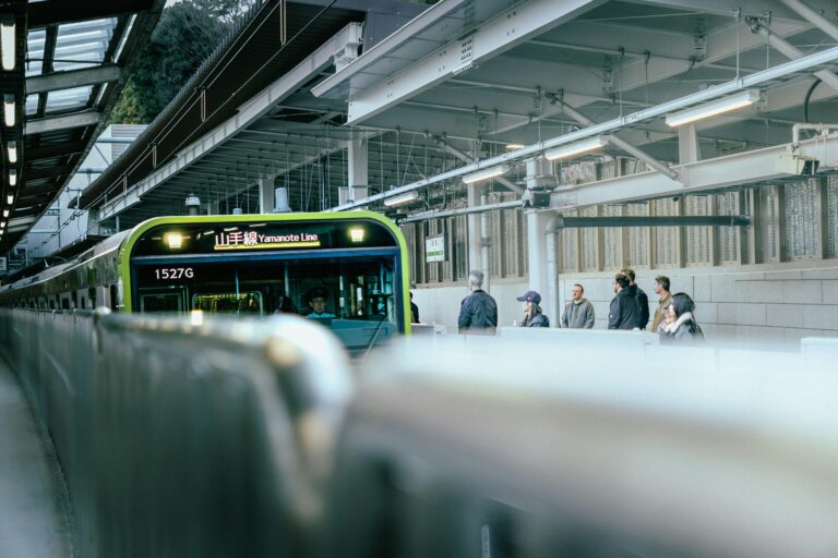 Travelers wait for the Yamanote Line train at a modern Tokyo station, capturing daily city life.