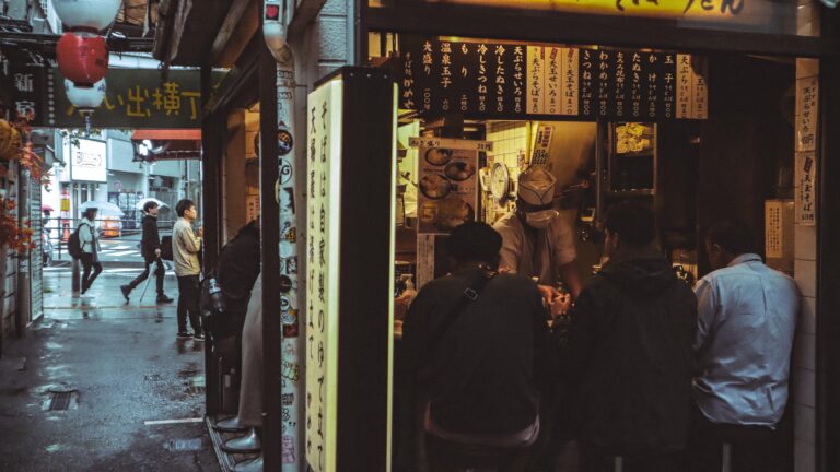 Night scene of a bustling Japanese street food stall in Shinjuku City, Tokyo.
