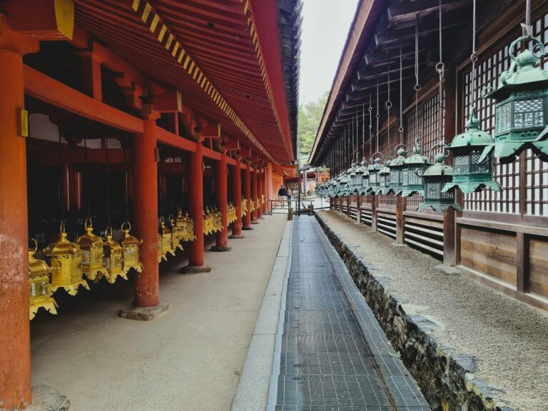 View of historic Japanese temple with traditional lanterns and red pillars, creating a serene atmosphere.