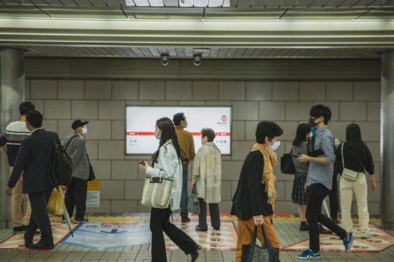 Masked commuters in Osaka subway station reflecting post-pandemic normalcy.